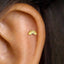 A gold-colored earring with a rainbow-colored design is visible in the person's ear.