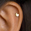 A small gold-colored earring with a dog-shaped charm is visible in the person's ear.