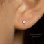 A close-up of a person's ear with a small heart-shaped earring attached.