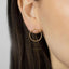A close-up view of a person's ear wearing a gold hoop earring.