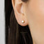 A close-up view of a person's ear with a small gold-colored earring in the earlobe.
