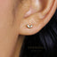 A close-up of a person's ear with a small heart-shaped earring in the earlobe.