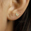 A close-up of a person's ear with a small gold-colored earring featuring a butterfly design.
