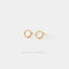 A pair of gold earrings with circular shapes on a white background.