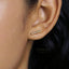 A close-up of a person's ear with a gold-colored earring inserted.