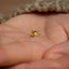 a tiny gold cat earring on someone's hand