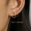 a close-up of a person's ear with two gold hoop earrings.
