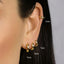 a close-up of a person's ear with multiple gold hoop earrings. The earrings are labeled with their sizes in millimeters: 6 mm, 7 mm, 8 mm, and 9 mm.