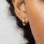 A close-up view of a person's ear with a gold hoop earring.
