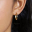 A close-up of a person's ear wearing a gold hoop earring.