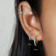 A close-up of a person's ear with three hoop earrings, each measuring 8 millimeters in size.