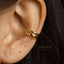 A close-up of a person's ear with a gold-colored ear cuff or earring.