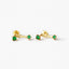 A pair of gold earrings with green gemstones, specifically emeralds, hanging from the ear hooks.