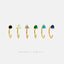 a row of gold earrings with various colored gemstones, including black, green, blue, and white stones.