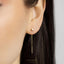 A close-up of a person's ear wearing a pair of gold earrings with a star-shaped charm hanging from the chain.
