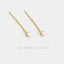 A pair of gold earrings with a crescent moon charm hanging from the chain.