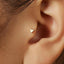A close-up view of a person's ear, showing a small heart-shaped earring in the earlobe.