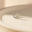 A silver horseshoe earring is resting on a light-colored surface.