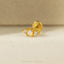 A gold-colored earring with a gemstone in the center, resting on a white surface.