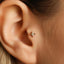 A close-up view of a person's ear, showing a small gold-colored earring with a star-shaped design.