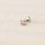 A single pink diamond-shaped gemstone is resting on a white fabric surface.