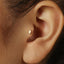 A close-up view of a person's ear, focusing on the tiniest gold-colored earring.