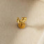 A small golden earring in the shape of a cat is shown against a light-colored background.