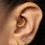 A gold earring with a bat-shaped design is visible in the person's ear.