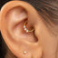 A close-up view of a person's ear with a gold hoop earring and a small diamond earring.