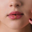 A close-up of a person's lips with a gold ring piercing in the middle of the lip.