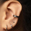 a close-up view of a person's ear adorned with multiple piercings, including a hoop earring and a ring earring.