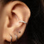 A close-up view of a person's ear adorned with multiple piercings, including a hoop earring and a small ear piercing.