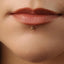 A close-up of a person's lips with a gold-colored piercing in the lower lip area.