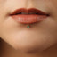 A close-up of a person's lips with a small green gemstone inserted in the lip.