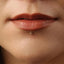 A close-up of a person's lips with a small gold-colored stud or piercing in the lower lip area.