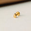 A small gold earring is resting on a white surface.
