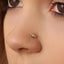 A close-up of a person's nose with a decorative nose ring featuring three stones.