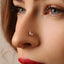 A close-up of a woman's face, focusing on her nose and lips. She has a nose piercing with a small, clear stone or crystal accent.