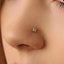 A close-up of a person's nose with a small gold-colored nose stud or clip adorned with small diamonds.