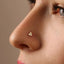 A close-up of a person's nose with a small gold-colored triangle-shaped piercing.