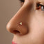 A close-up of a person's nose with a small gold-colored triangle-shaped piercing.