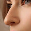 A close-up of a person's nose with a small yellow gemstone or piercing in it.