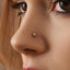 A close-up of a person's nose with a small gold-colored nose stud featuring a star-shaped design.