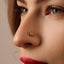 A close-up of a woman's face, focusing on her nose and lips. She has a gold nose ring with a floral design.