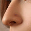 A close-up of a person's nose with a small, colorful gemstone or piercing in it.