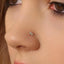A close-up of a person's nose with a small, delicate nose stud featuring two small diamonds.