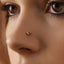 A close-up of a person's face, focusing on their nose and the gold-colored nose ring.