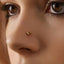 A close-up of a person's face, focusing on their nose and the gold-colored nose ring.