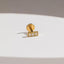 A gold-colored earring with three small diamonds set in it, resting on a white surface.