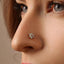 A close-up of a woman's face, focusing on her nose and the small, ornate nose ring with a flower-shaped stone.